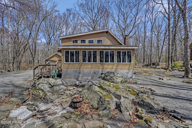 view of front facade with a deck, a chimney, and a sunroom