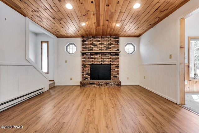 unfurnished living room featuring a fireplace, a wainscoted wall, wood finished floors, and a baseboard radiator