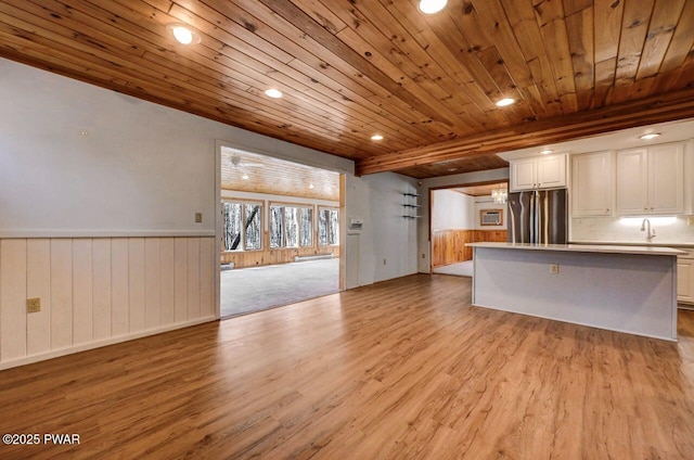 unfurnished living room with recessed lighting, wood ceiling, wainscoting, light wood finished floors, and wooden walls