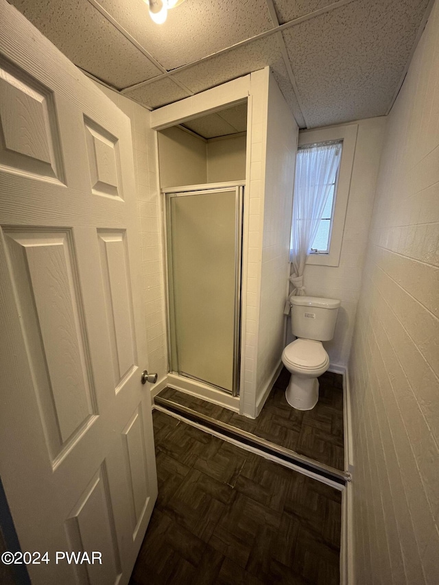 bathroom featuring a paneled ceiling, toilet, parquet floors, and walk in shower