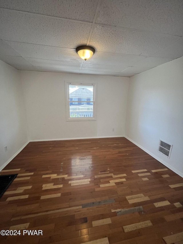 empty room with a paneled ceiling and dark hardwood / wood-style floors