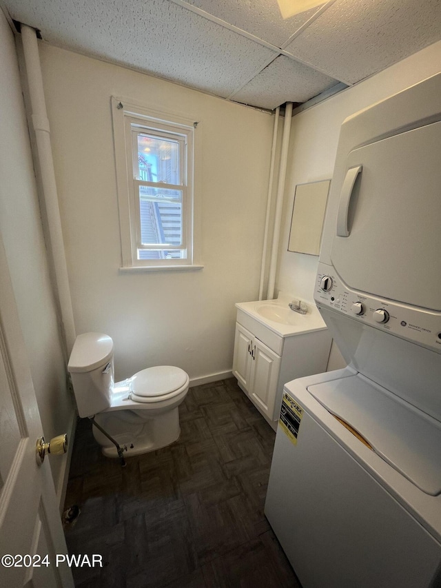 laundry room with dark parquet floors, stacked washing maching and dryer, and sink