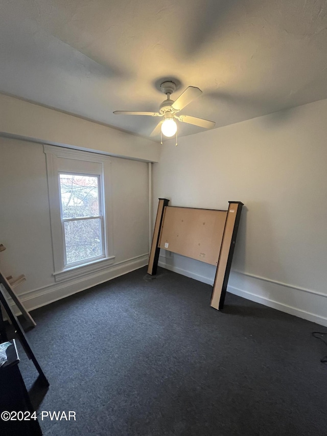 unfurnished bedroom featuring dark colored carpet and ceiling fan