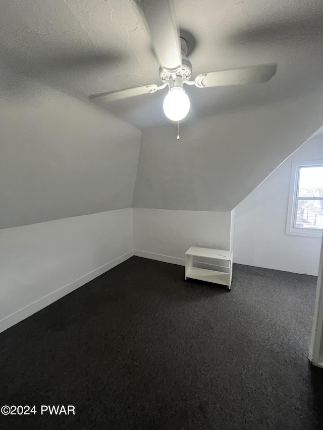 additional living space with ceiling fan, dark carpet, and lofted ceiling