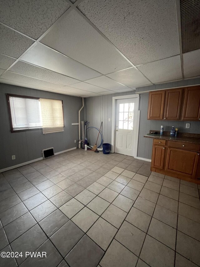 interior space with light tile patterned floors and a paneled ceiling