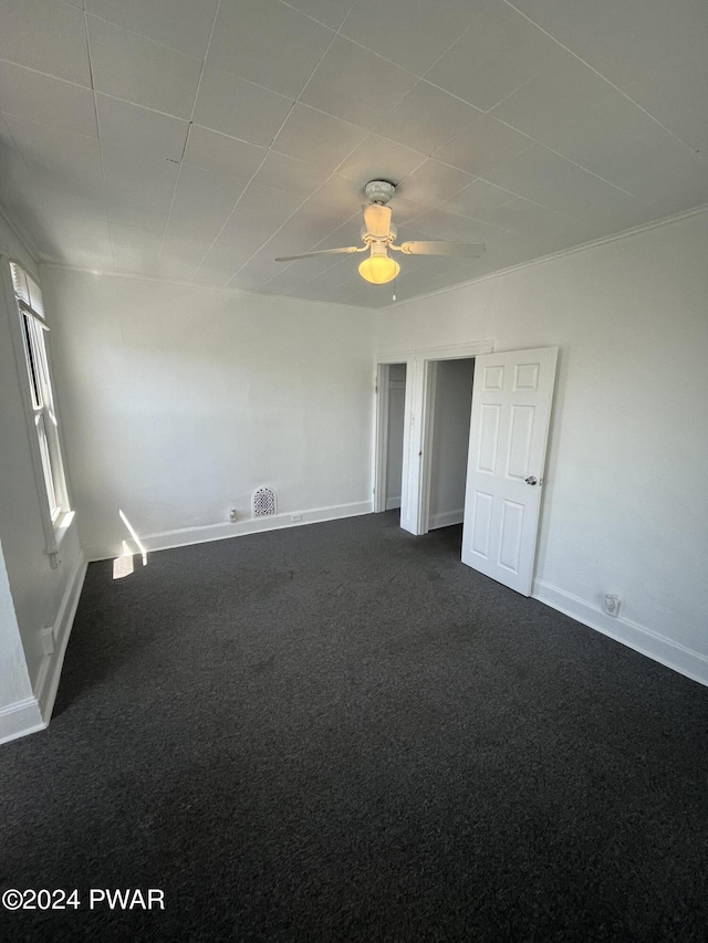 spare room featuring ceiling fan and dark carpet