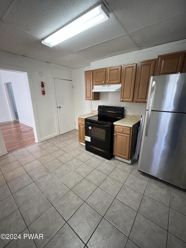 kitchen featuring stainless steel fridge, black range with electric cooktop, a drop ceiling, and light tile patterned flooring