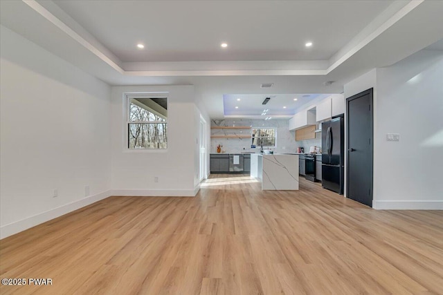328 Forest Dr, Lords Valley, PA 18428 - unfurnished living room featuring a tray ceiling and light wood-type flooring