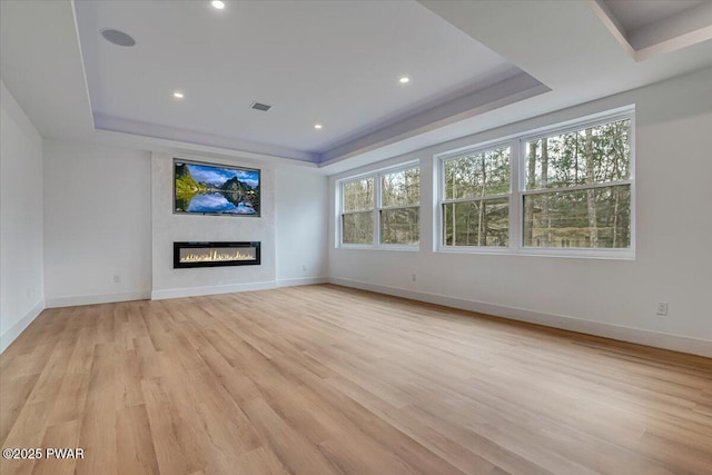 328 Forest Dr, Lords Valley, PA 18428 - unfurnished living room with a raised ceiling, a glass covered fireplace, light wood-style floors, and recessed lighting
