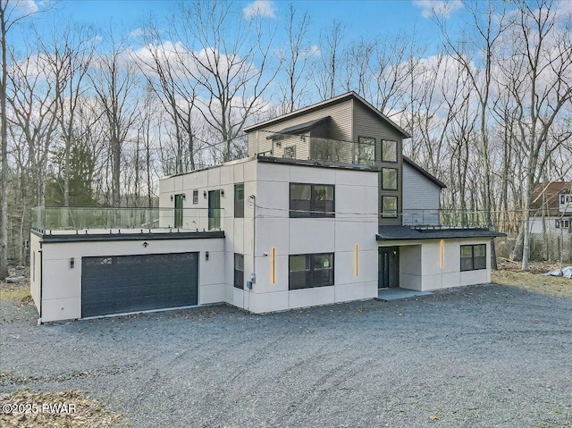 328 Forest Dr, Lords Valley, PA 18428 - modern home with gravel driveway, a garage, stucco siding, and a balcony