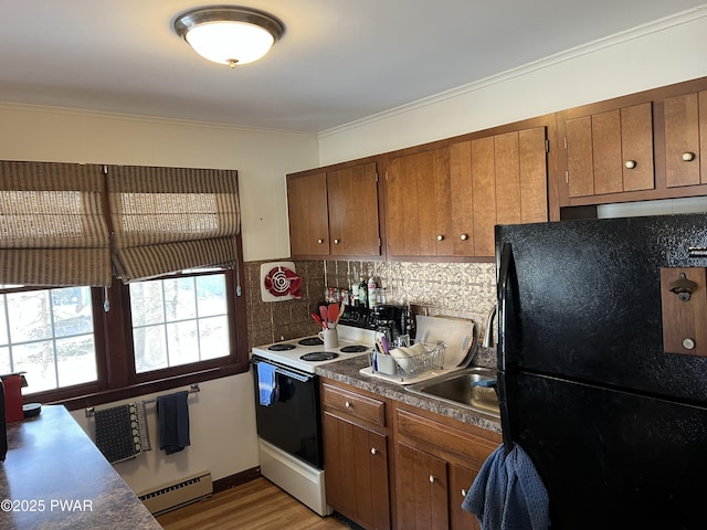 kitchen with range with electric cooktop, baseboard heating, freestanding refrigerator, brown cabinets, and tasteful backsplash