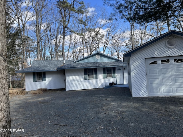 single story home featuring a shingled roof, driveway, and a garage