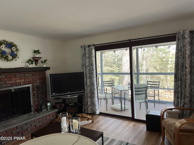 living area with ornamental molding, a brick fireplace, and light wood-style floors