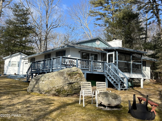 view of front of house featuring a deck, a sunroom, a chimney, and stairs