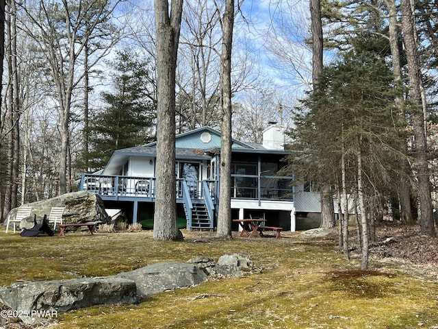 back of property featuring a sunroom, stairs, a chimney, and a deck