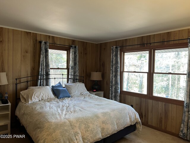 carpeted bedroom with wood walls and ornamental molding