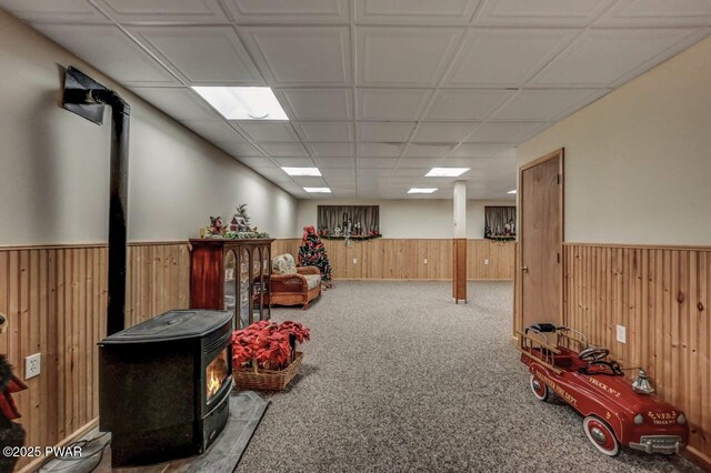 107 Musket Dr, Lackawaxen, PA 18435 - sitting room featuring a wood stove, a wainscoted wall, carpet floors, and wooden walls
