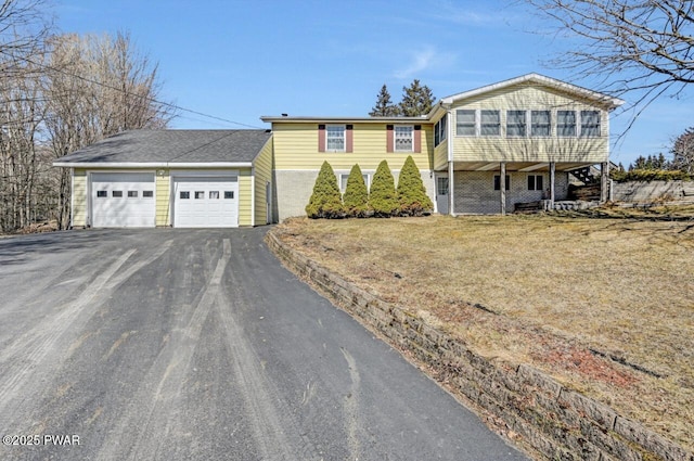 view of front of home featuring aphalt driveway, an attached garage, and a sunroom