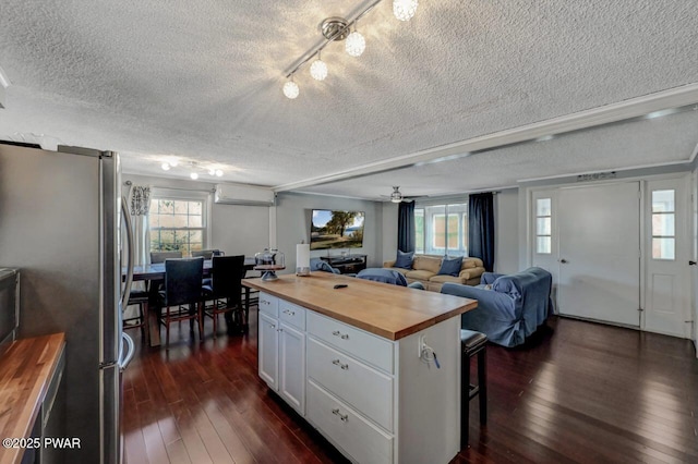 kitchen with a wall mounted AC, dark wood-style flooring, freestanding refrigerator, and butcher block countertops