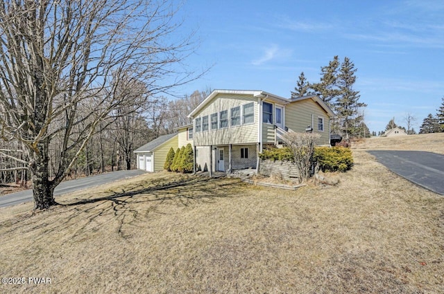 view of front of property featuring a detached garage and an outbuilding