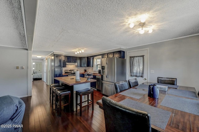 dining room featuring a textured ceiling, dark wood finished floors, and crown molding