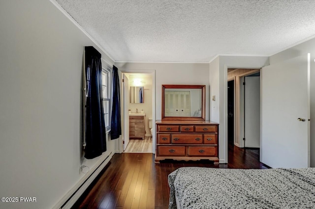 bedroom with connected bathroom, a textured ceiling, dark wood-style floors, and ornamental molding