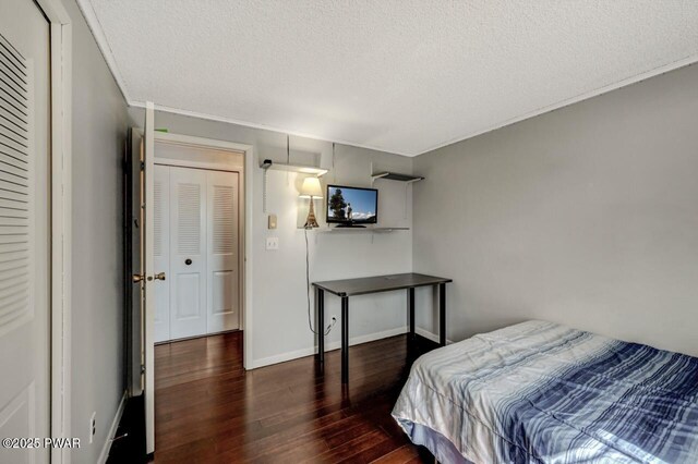 bedroom with wood finished floors, baseboards, and a textured ceiling