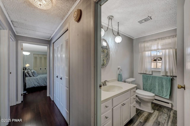 bathroom with baseboard heating, ornamental molding, toilet, and wood finished floors