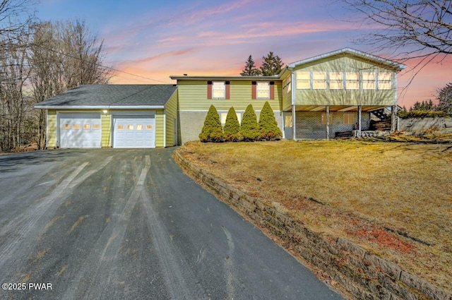 view of front facade featuring stairs, a garage, a lawn, and driveway