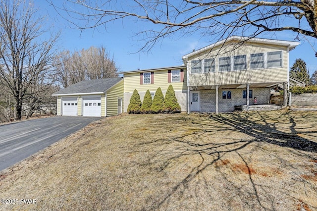 tri-level home featuring a garage, brick siding, and an outdoor structure