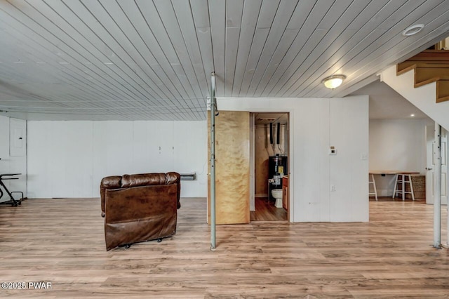 finished basement featuring electric panel, water heater, wood ceiling, and wood finished floors