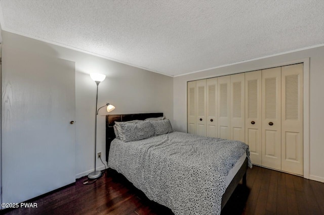 bedroom with dark wood finished floors, baseboards, a closet, and a textured ceiling