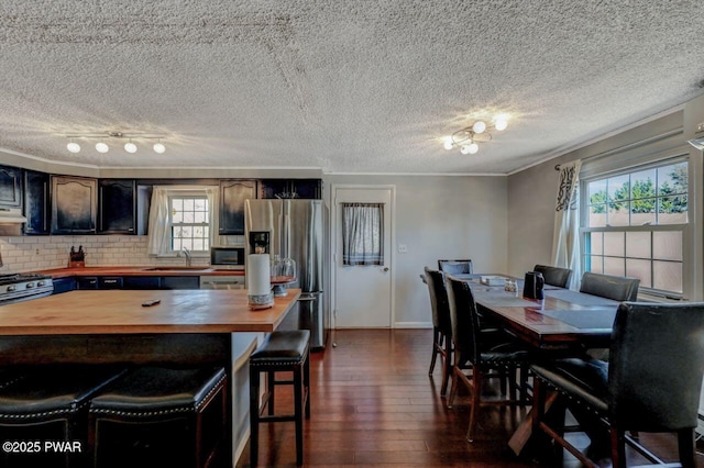 dining area with baseboards, a textured ceiling, dark wood-style floors, and crown molding