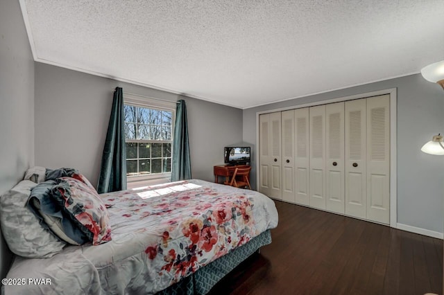 bedroom featuring wood finished floors, baseboards, ornamental molding, a closet, and a textured ceiling