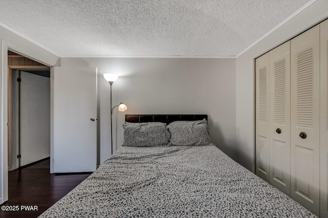 bedroom featuring a closet, a textured ceiling, dark wood-style flooring, and crown molding