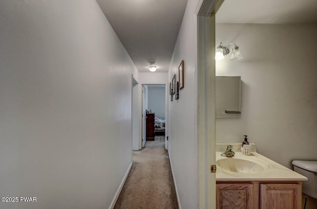 hall with sink and light colored carpet