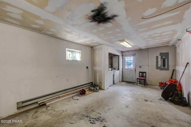 basement featuring separate washer and dryer, a wealth of natural light, electric panel, and baseboard heating