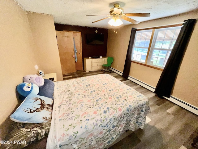 bedroom with a textured ceiling, dark hardwood / wood-style floors, ceiling fan, and a baseboard heating unit