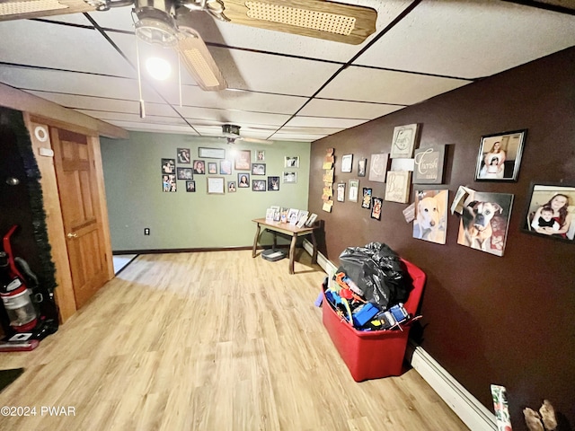 rec room featuring hardwood / wood-style floors, a paneled ceiling, and a baseboard radiator