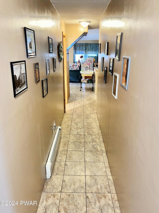 hall with light tile patterned floors, a textured ceiling, and a baseboard heating unit