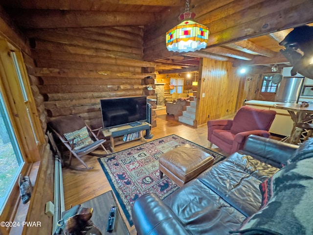 living room with wooden walls, light wood-type flooring, rustic walls, beam ceiling, and wood ceiling