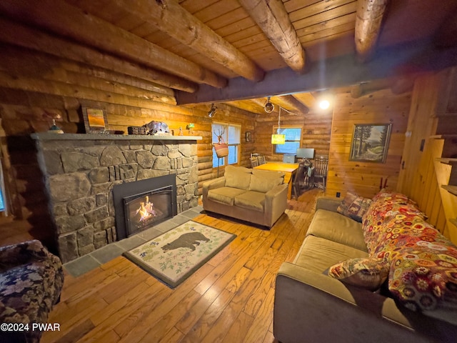 living room with light wood-type flooring, a fireplace, rustic walls, beam ceiling, and wood ceiling