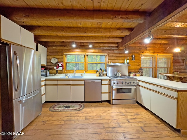 kitchen featuring white cabinets, stainless steel appliances, rustic walls, and sink