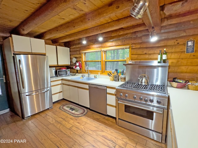 kitchen featuring sink, light hardwood / wood-style flooring, rustic walls, appliances with stainless steel finishes, and white cabinetry