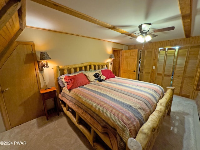 carpeted bedroom featuring ceiling fan and wooden walls