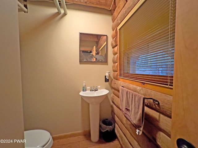 bathroom featuring sink, log walls, and toilet