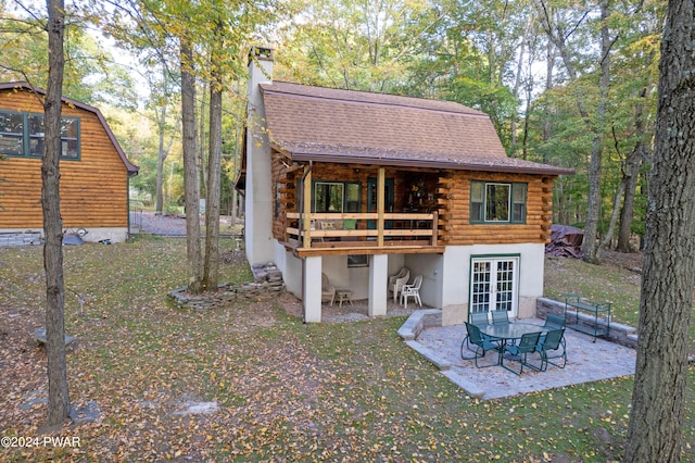 rear view of property featuring a lawn, a patio, a wooden deck, and french doors