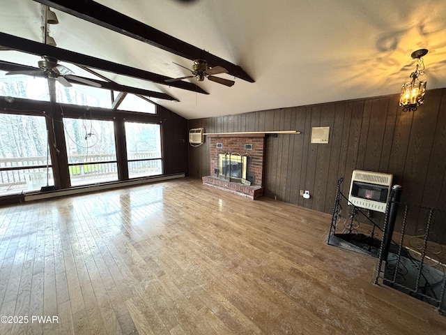 unfurnished living room with lofted ceiling with beams, wooden walls, hardwood / wood-style floors, a brick fireplace, and heating unit