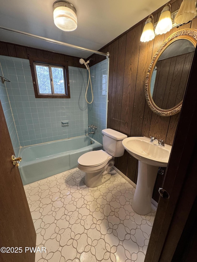 full bathroom with wooden walls, toilet, and tiled shower / bath