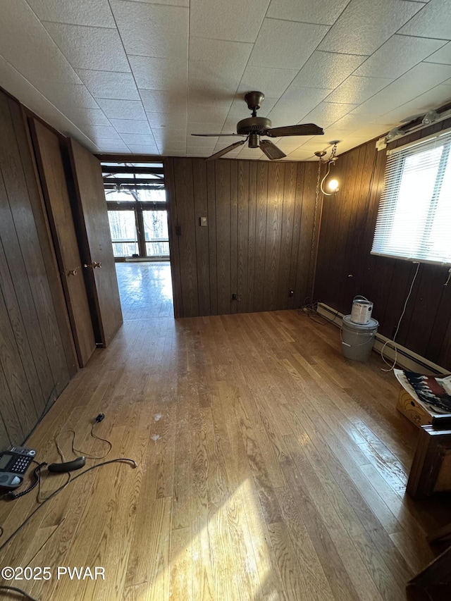 unfurnished room with french doors, ceiling fan, light hardwood / wood-style floors, and wooden walls